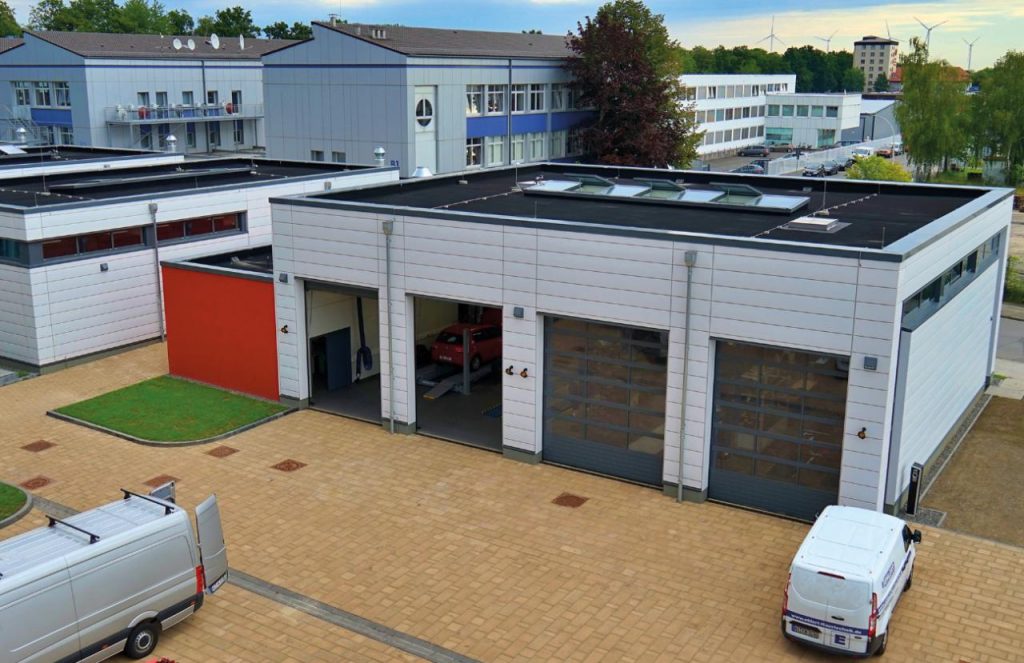 Luftaufnahme eines modernen Werkstattgebäudes mit mehreren Hallentoren und Flachdach mit Oberlichtern